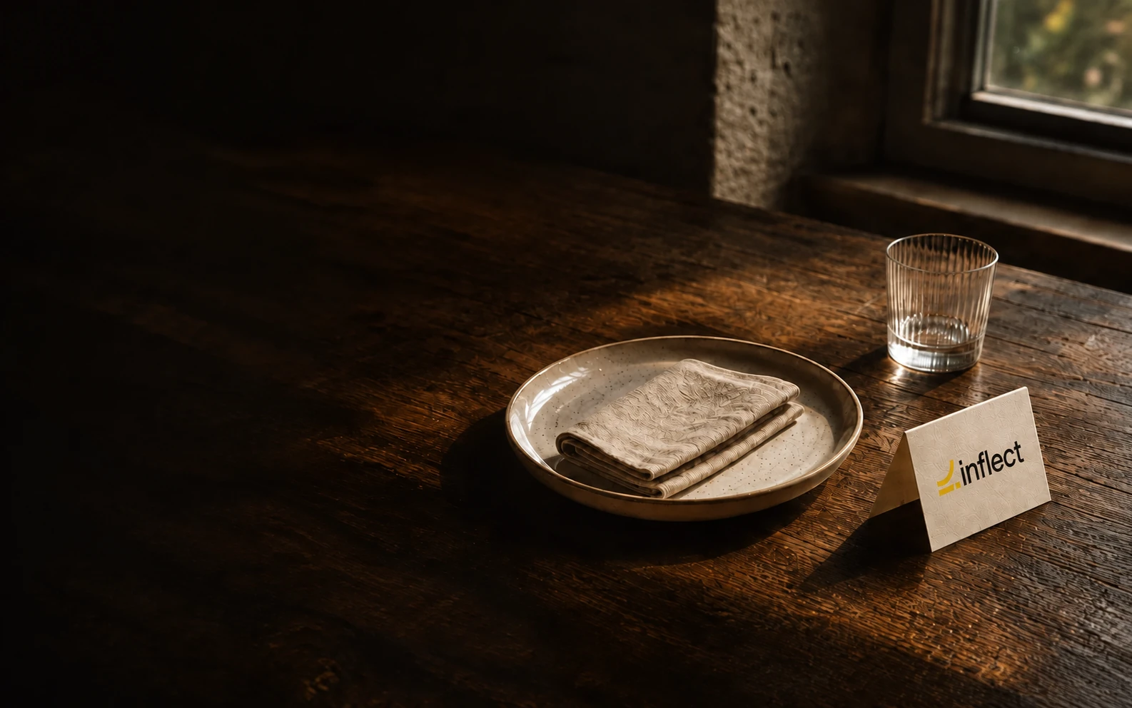A quiet table setting with linen, a glass, and an Inflect place card.